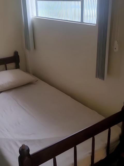 A cama de solteiro do Quarto 2, embaixo da janela.