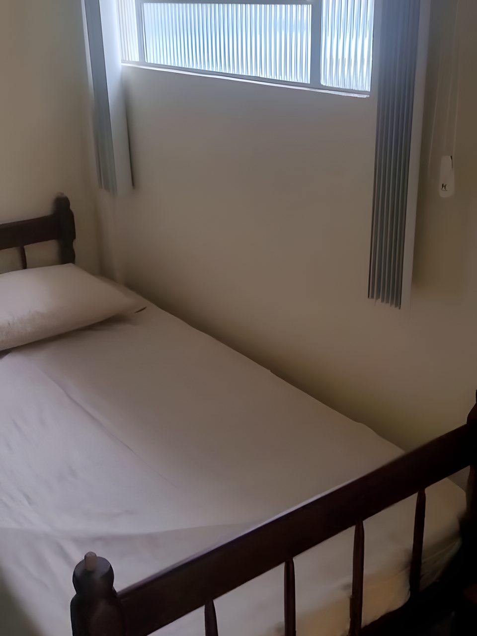 A cama de solteiro do Quarto 2, embaixo da janela.