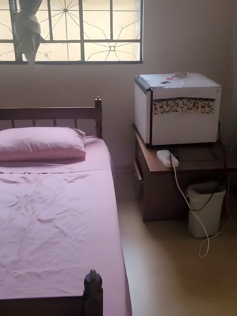 O frigobar ao lado da cama, no Quarto 3.