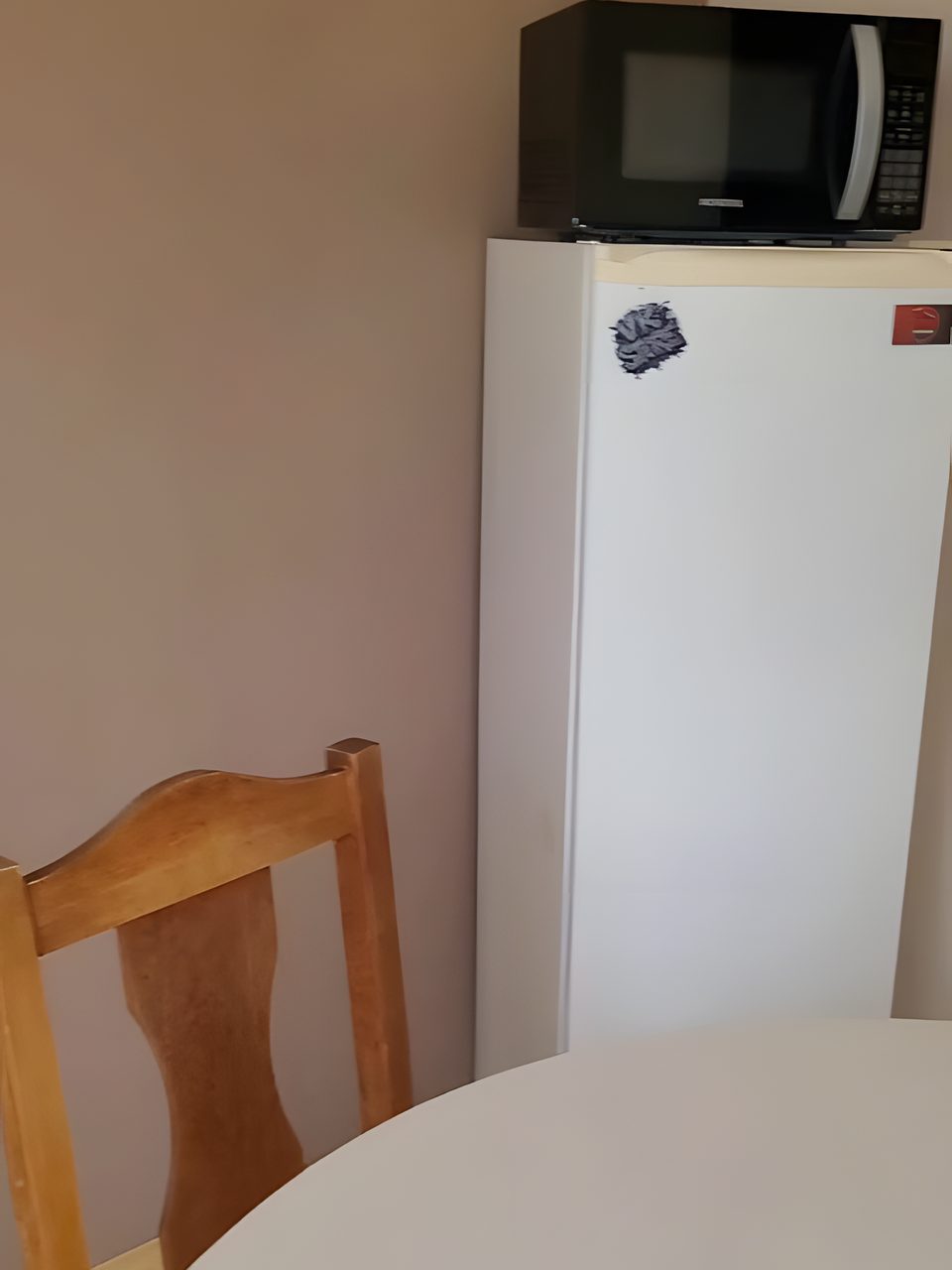 A copa do Quarto 4, com mesa redonda, geladeira e micro-ondas.