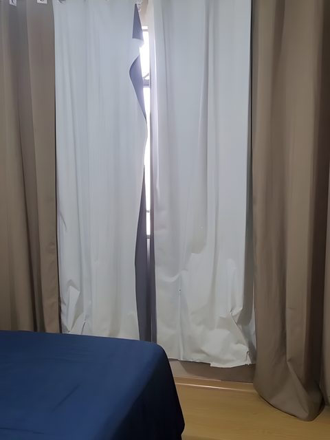 A janela com cortinas do Quarto 4, ao lado da cama.